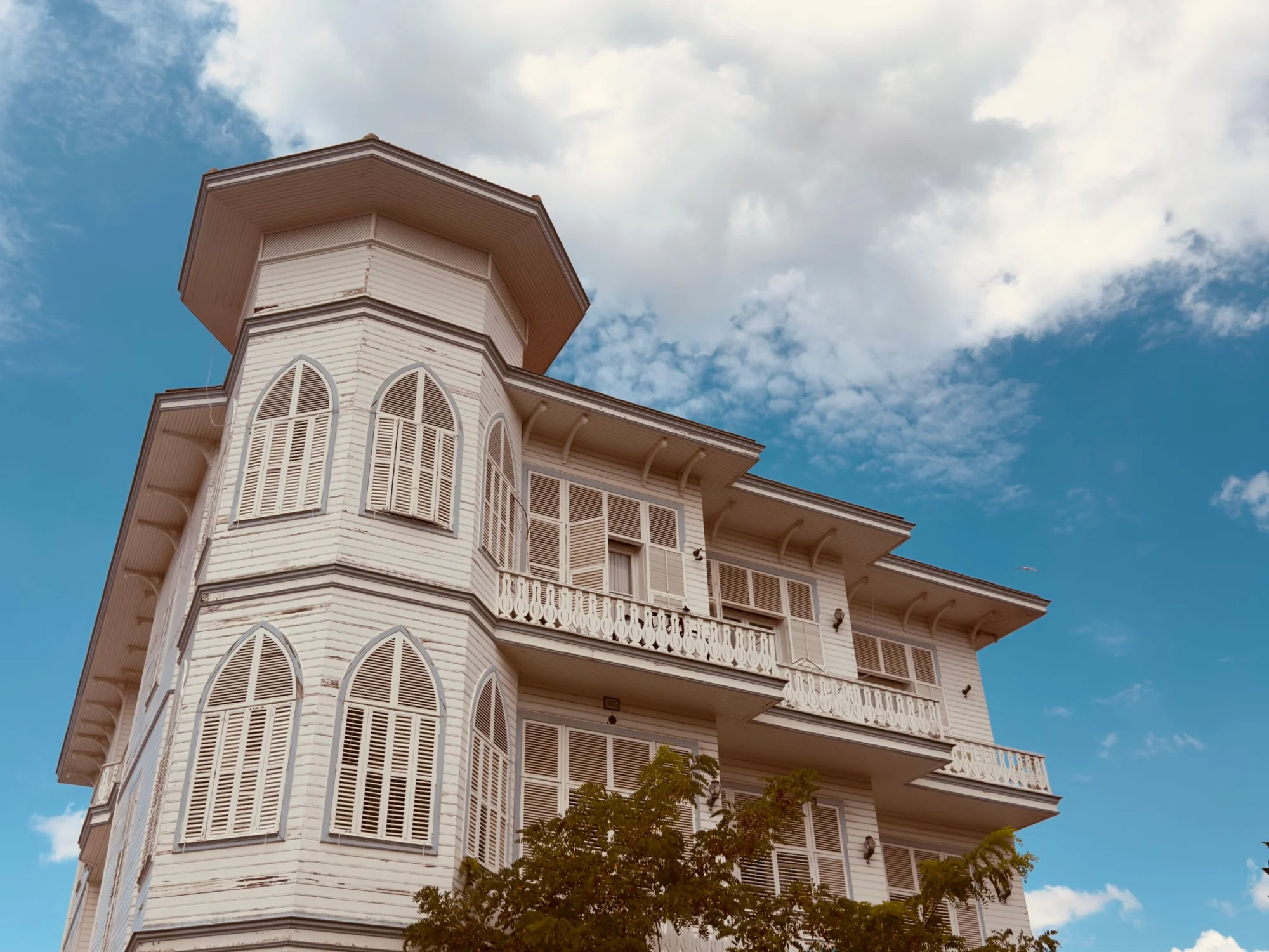 Elegant Ottoman-style mansion with intricate wooden architecture against a vibrant sky.