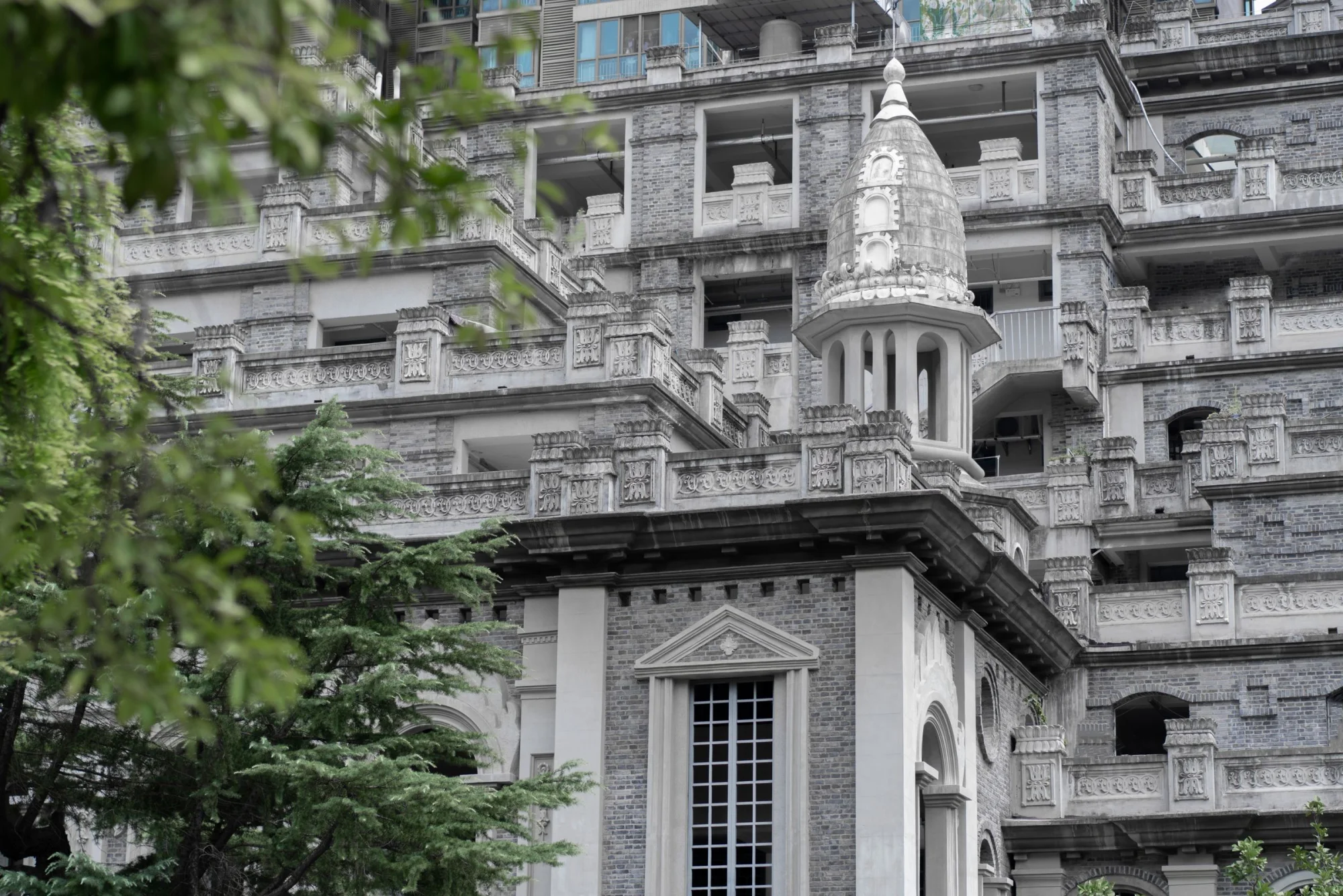 A detailed view of a historic mansion showcasing intricate stone facade with leafy greenery.