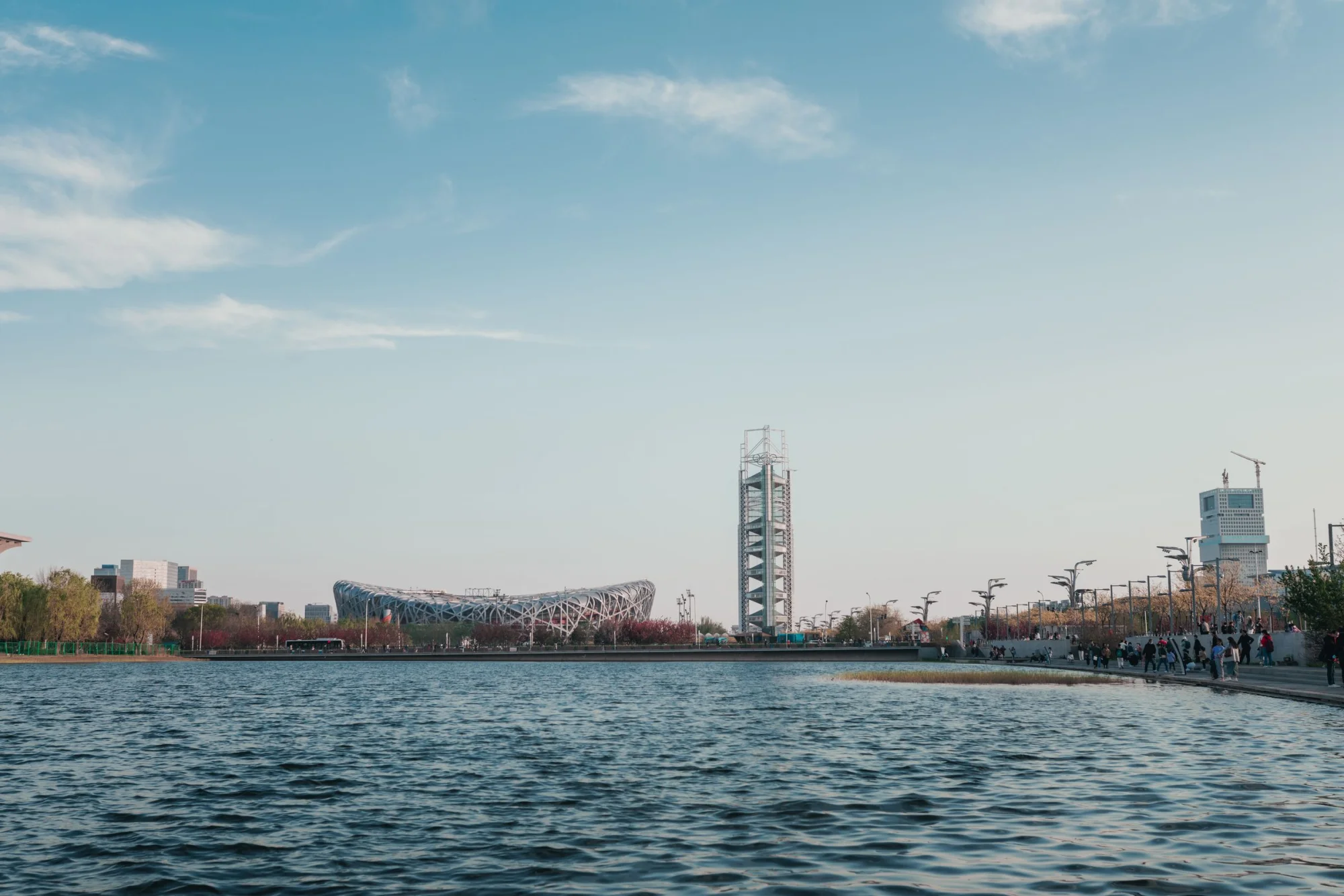 View of Beijing Olympic Park's Bird's Nest Stadium and Water Cube by a lake.