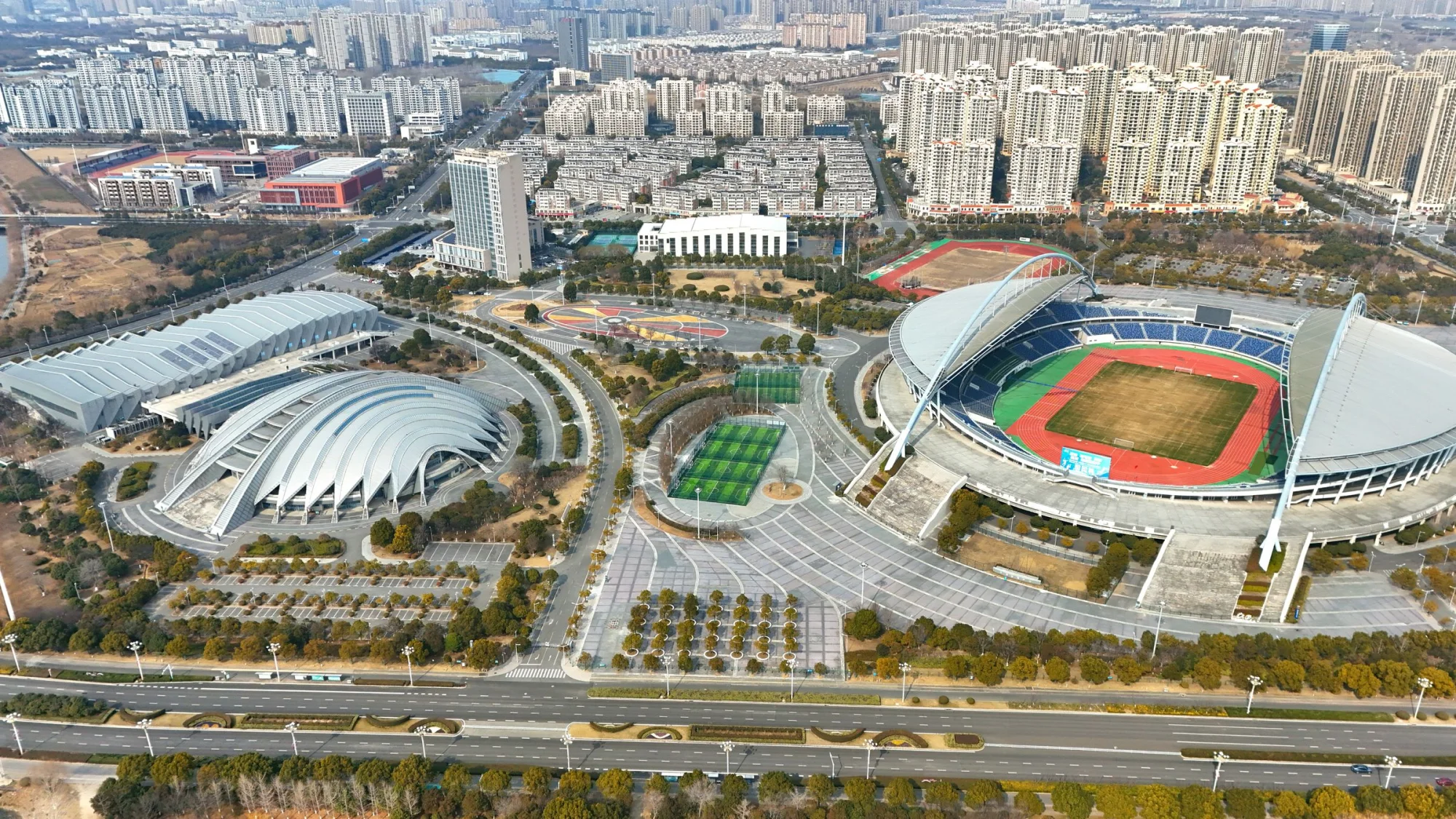Aerial view showcasing a large stadium with modern architecture amidst an expansive urban setting.