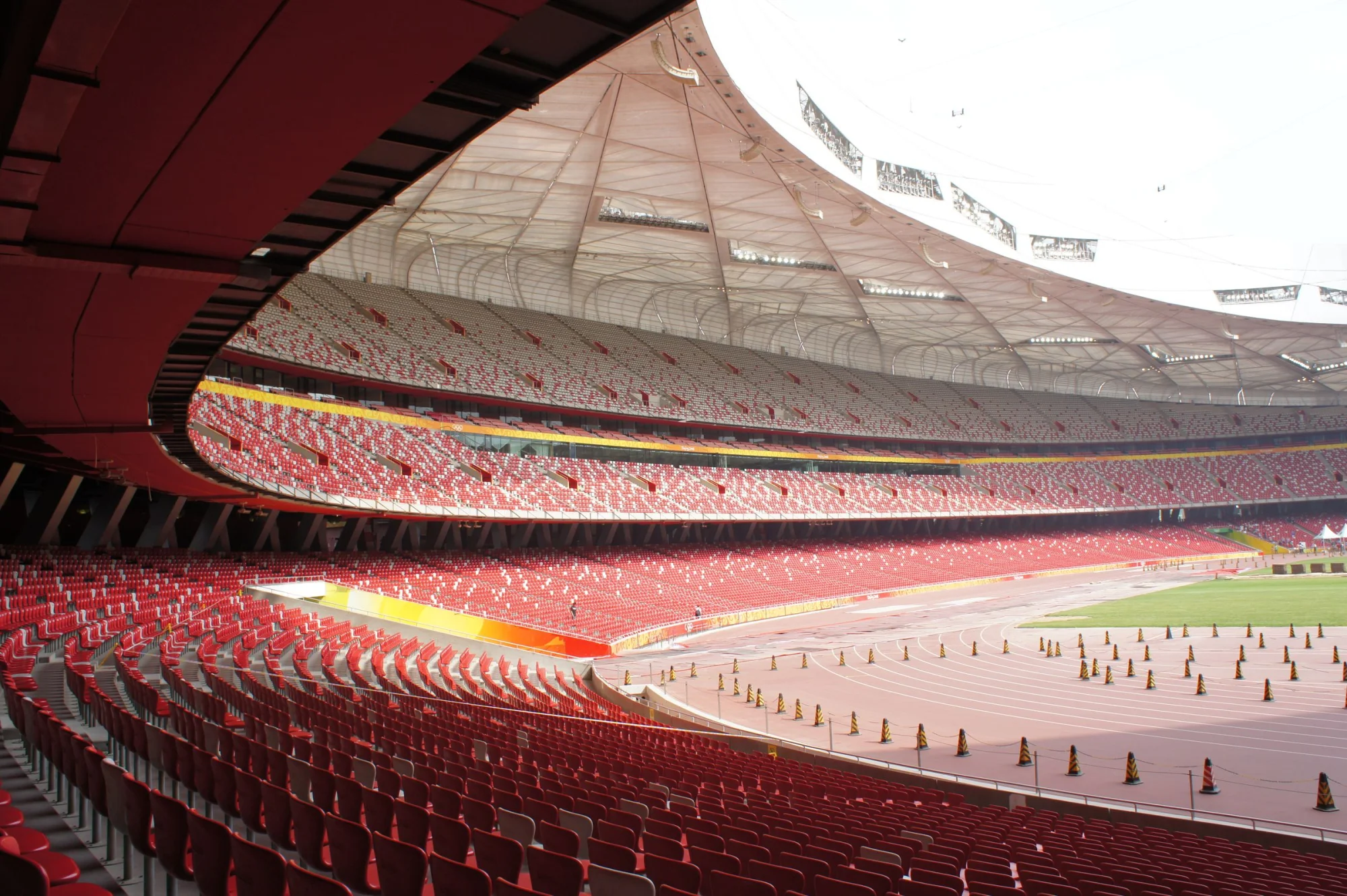 Empty seats and expansive view of Beijing National Stadium, bathed in daylight.