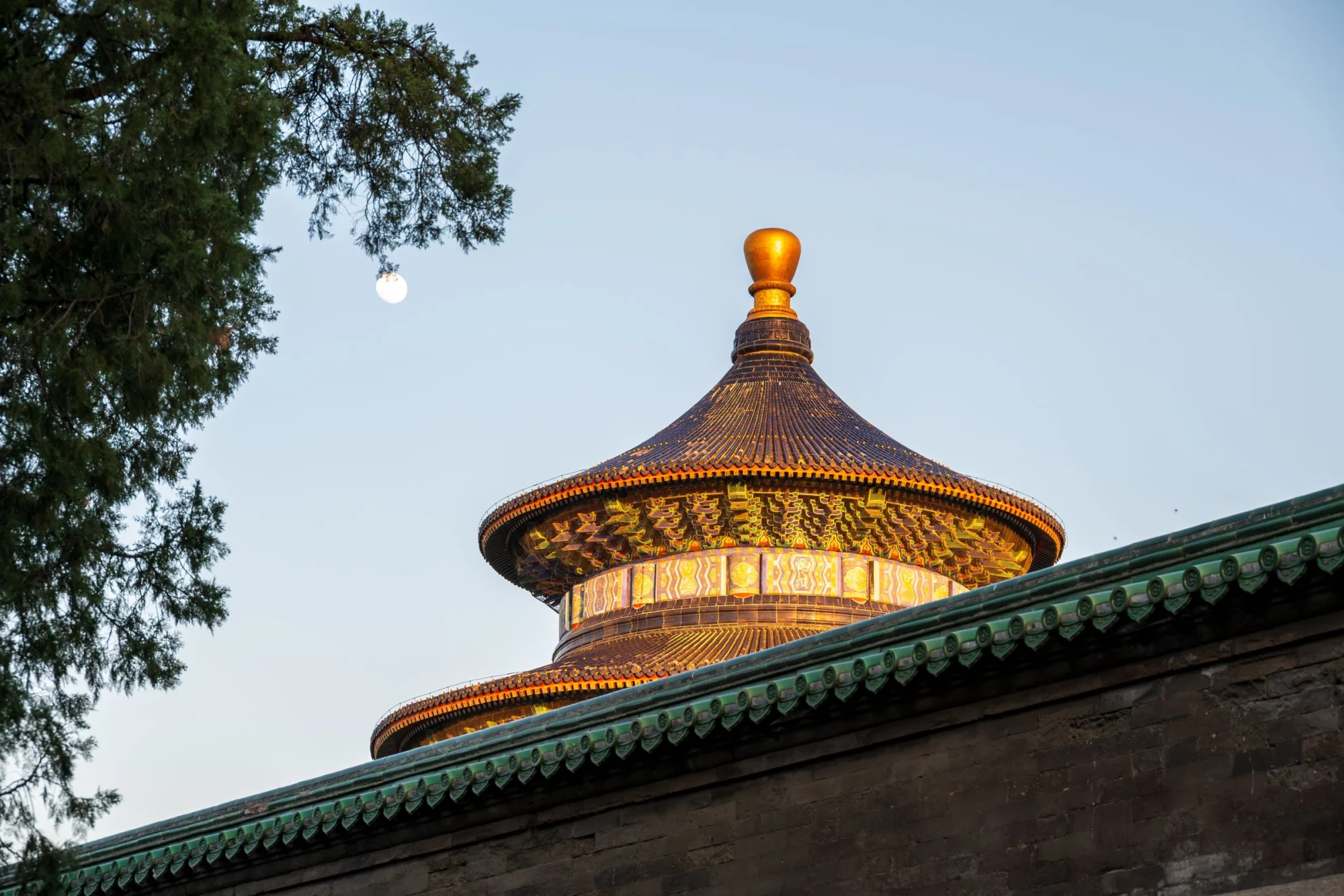 The Temple of Heaven in Beijing at sunset, showing its intricate roof design and surrounding wall.
