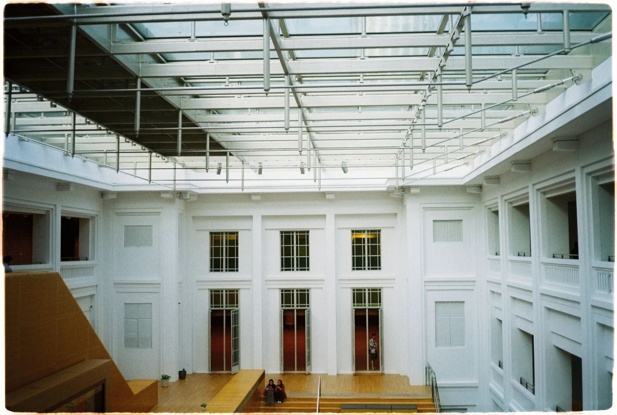Spacious atrium with glass roof at the National Gallery Singapore, showcasing modern architecture.