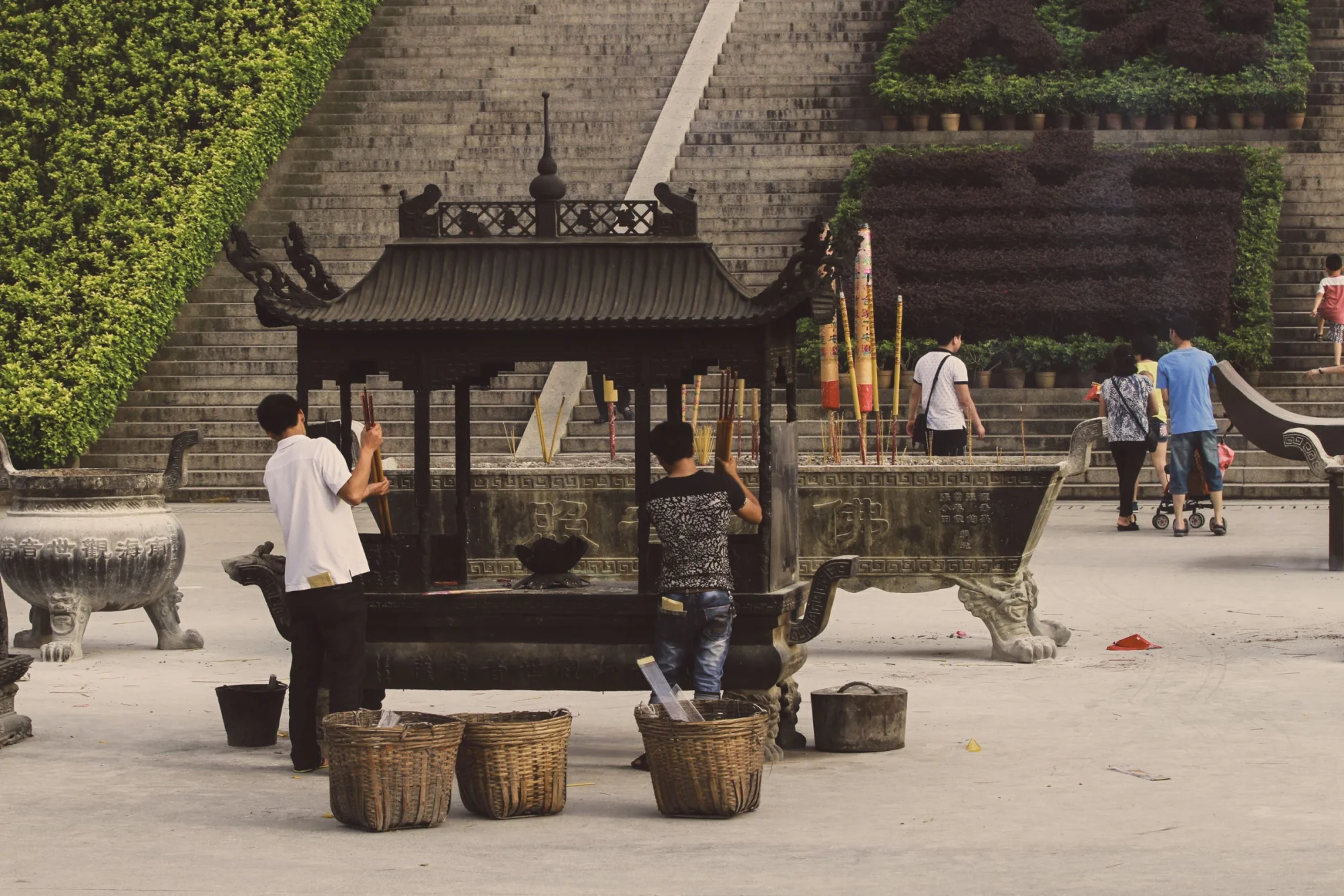 A group of people performing a spiritual ritual with incense at a traditional shrine outdoors.
