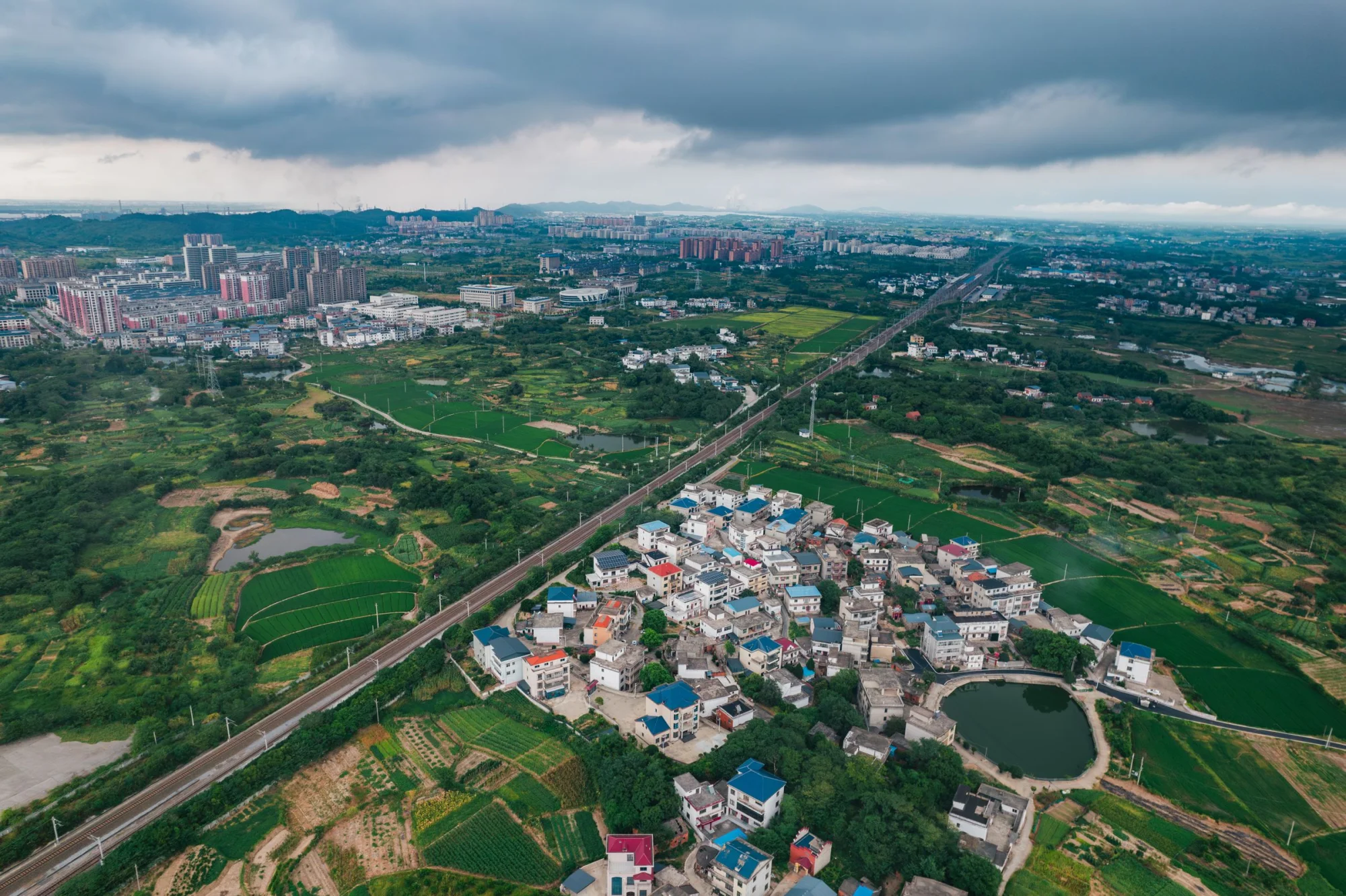 Scenic aerial view of suburban and cityscape areas in Jiujiang, Jiangxi, showcasing urban and rural landscapes.