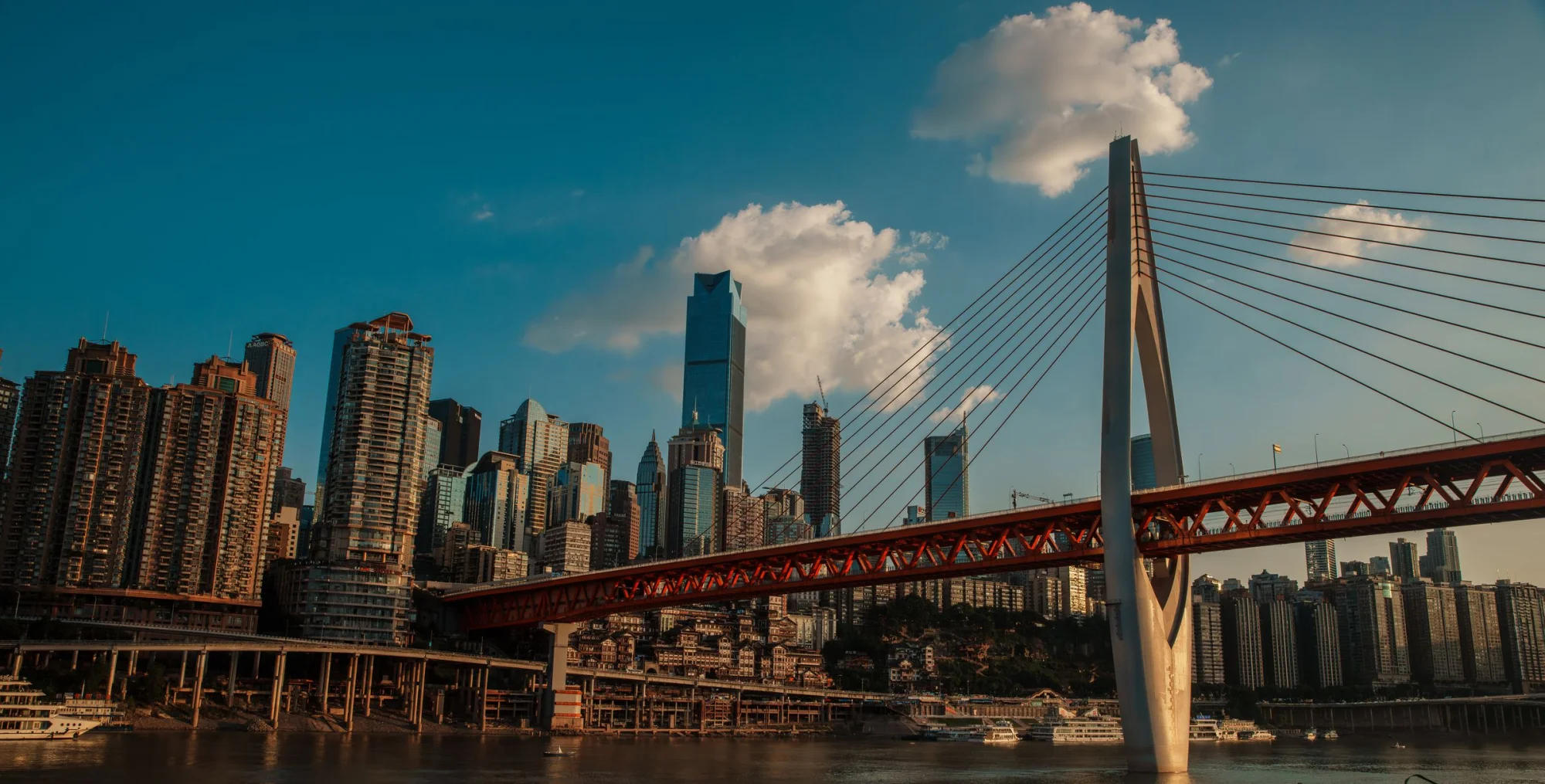 Stunning view of Chongqing's skyscrapers and the Yangtze River Bridge under a blue sky.