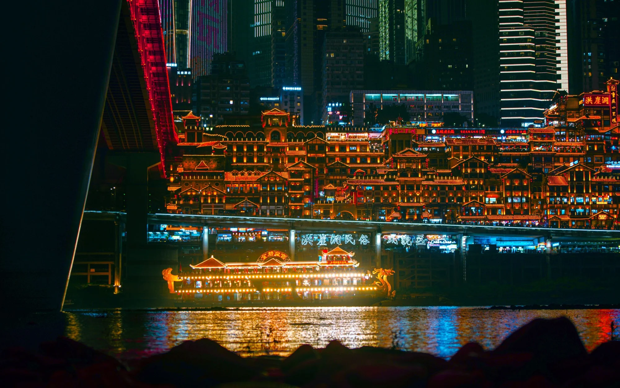 Vivid neon lights illuminate Chongqing's cityscape with reflections on the river, creating a cyberpunk atmosphere.