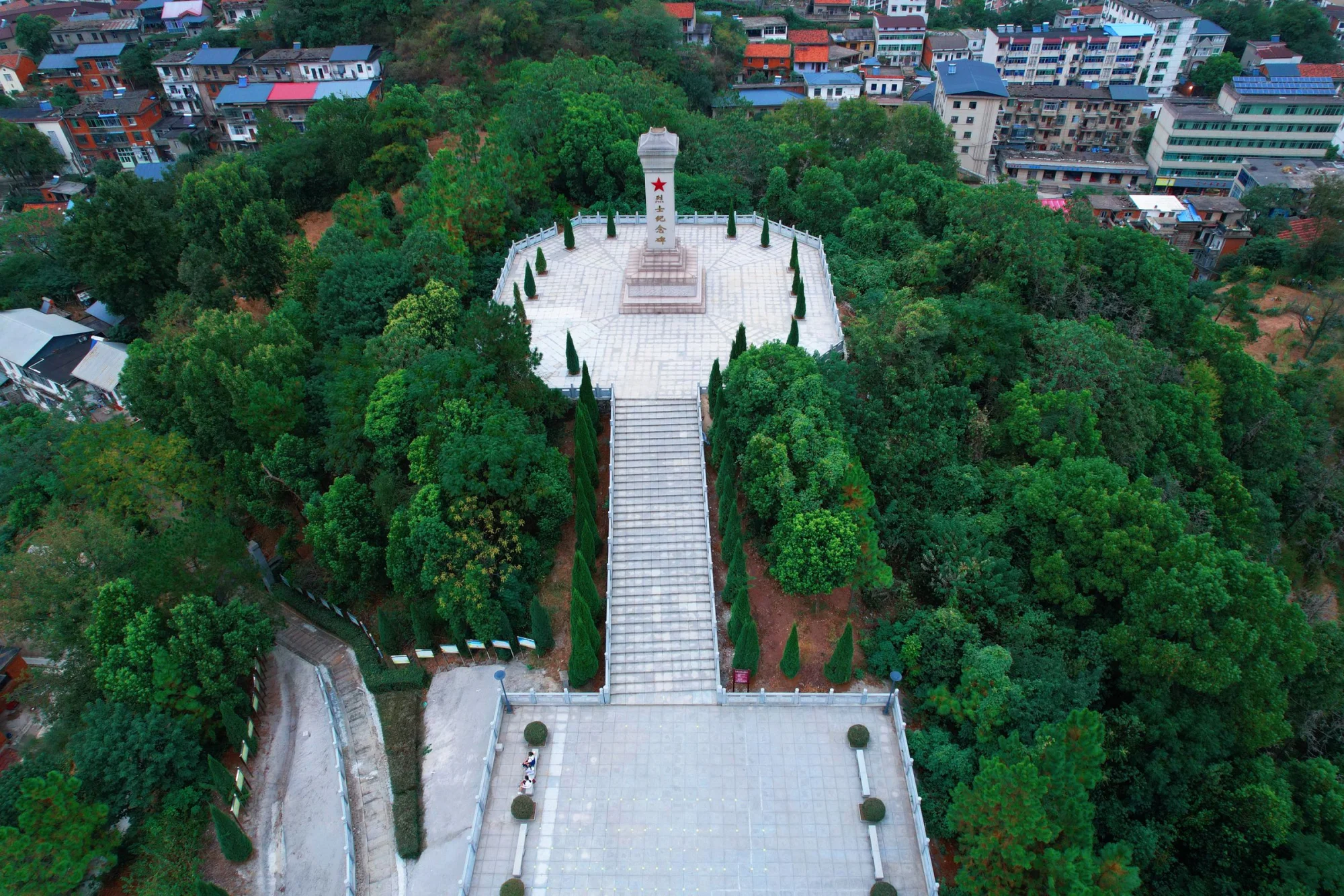 Aerial shot of a monument surrounded by greenery and urban landscape in Jiujiang, China.