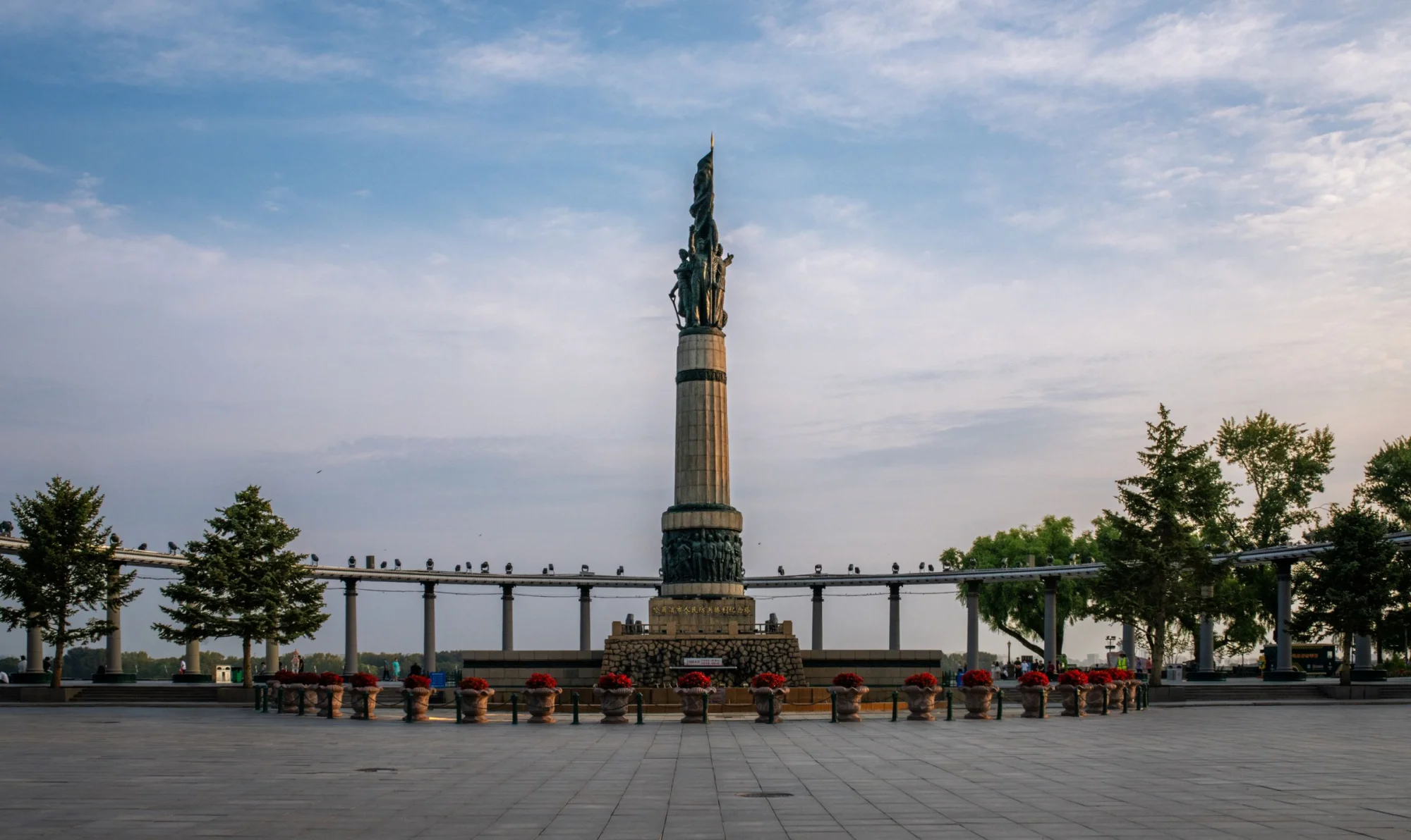 A majestic monument stands tall in a serene park setting against a clear sky.