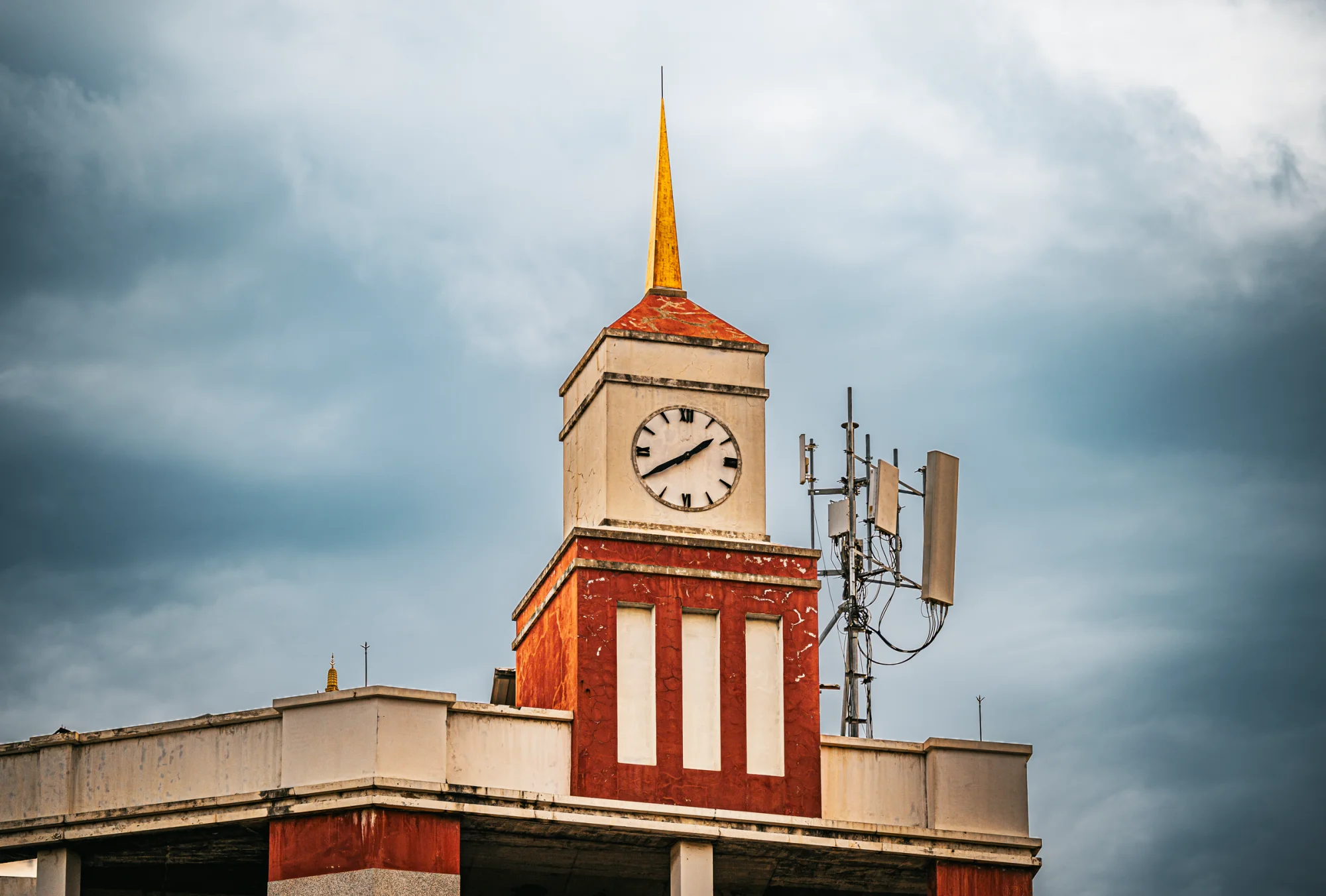 Iconic clock tower in Bangkok with dramatic clouds, showcasing urban architecture and technology.