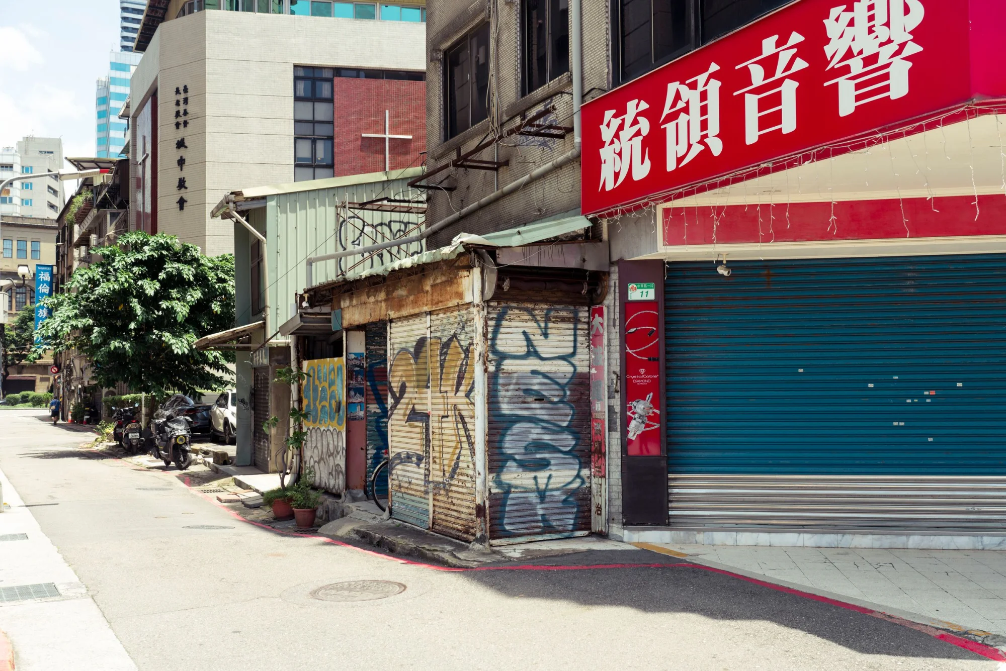 Urban Taipei street view with graffiti-covered buildings under bright daylight.