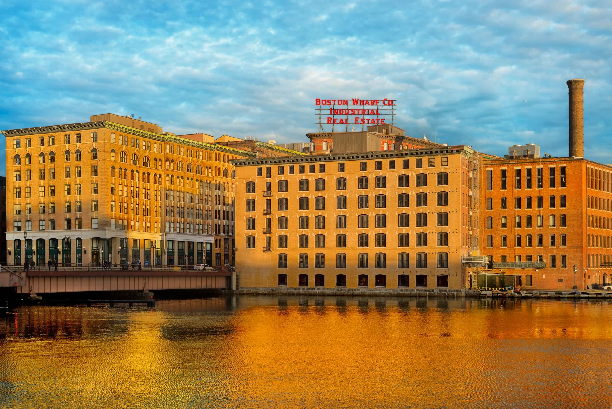 Captivating view of Boston Wharf's industrial architecture reflected in the river during daylight.