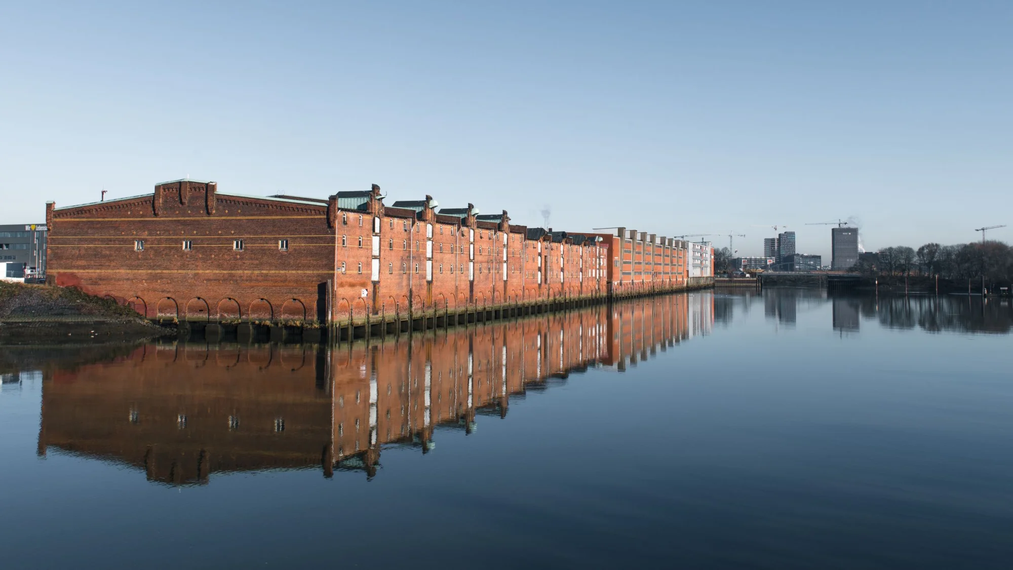 Scenic view of Hamburg's historic warehouses reflecting on the Elbe River.
