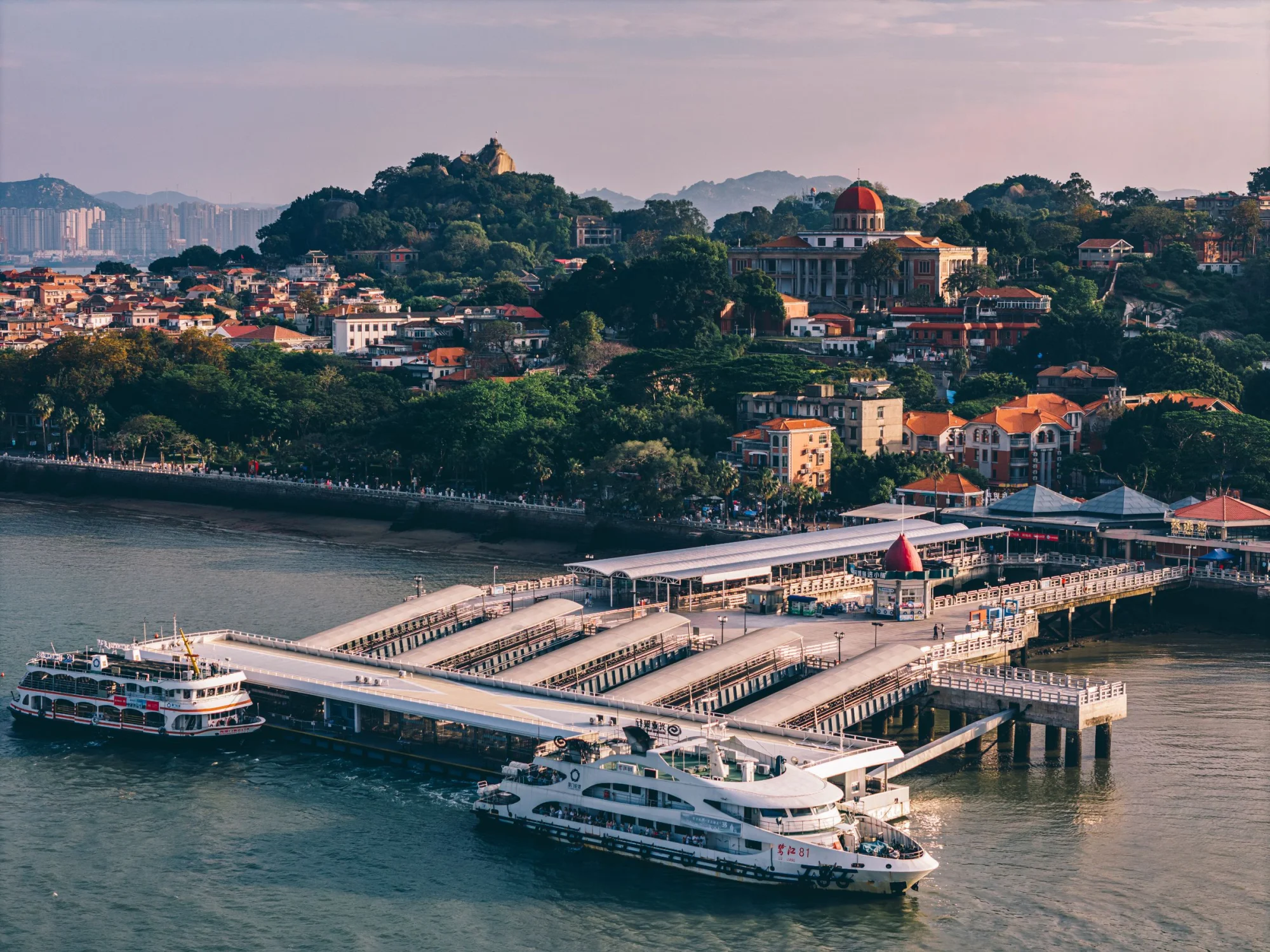 Aerial photograph showcasing the bustling harbor of Gulangyu Island with ferries and lush landscapes.
