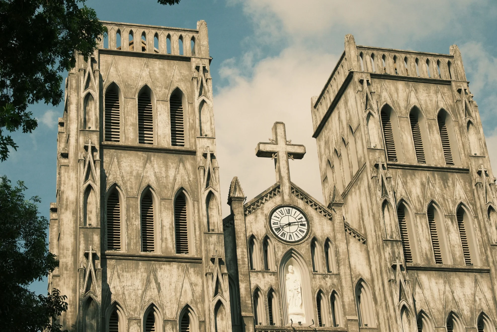 A striking Gothic-style cathedral in Beijing with prominent cross and clock tower under a bright sky.