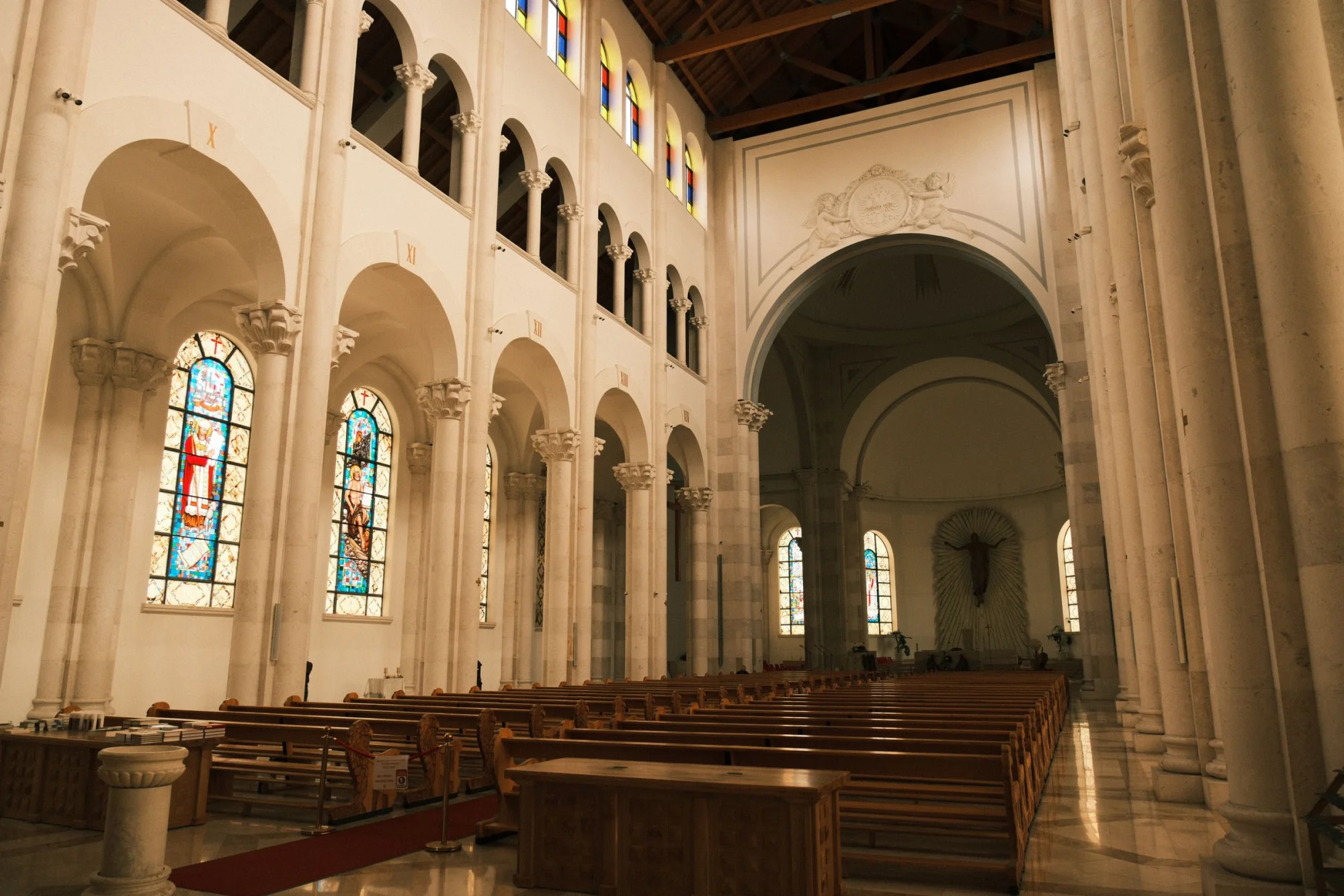 Capture of the beautiful interior of a cathedral in Priştine with stained glass windows and arches.