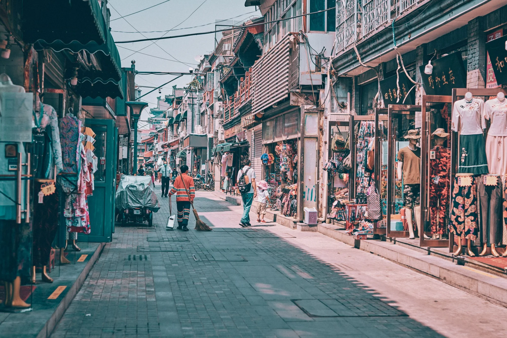 Vibrant street market scene in Beijing, showcasing local shops and pedestrians on a sunny day.