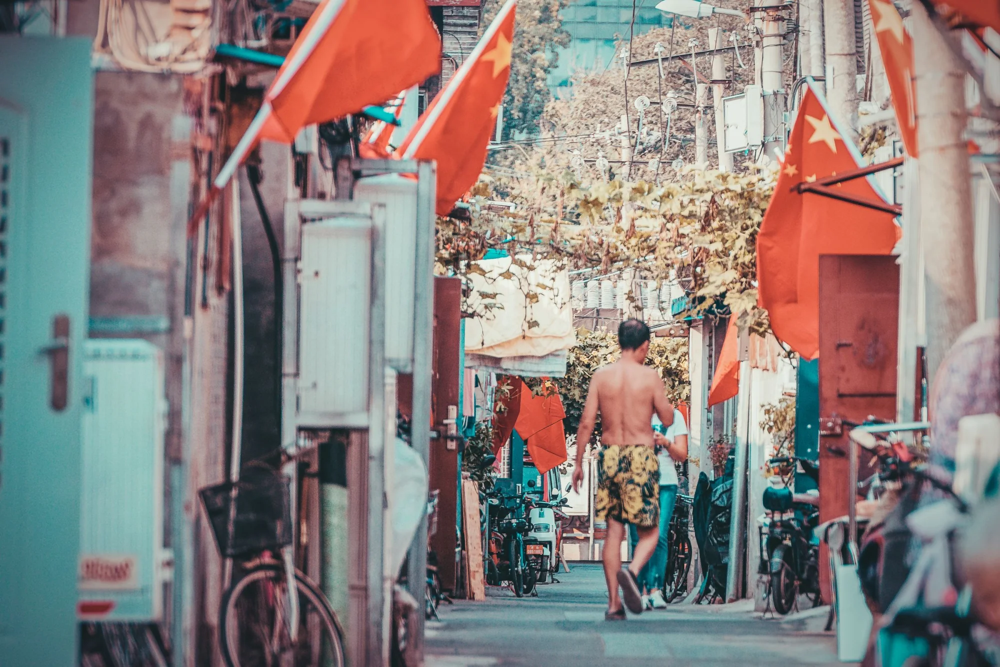 A vibrant street in Beijing featuring flags and a person walking during daylight.