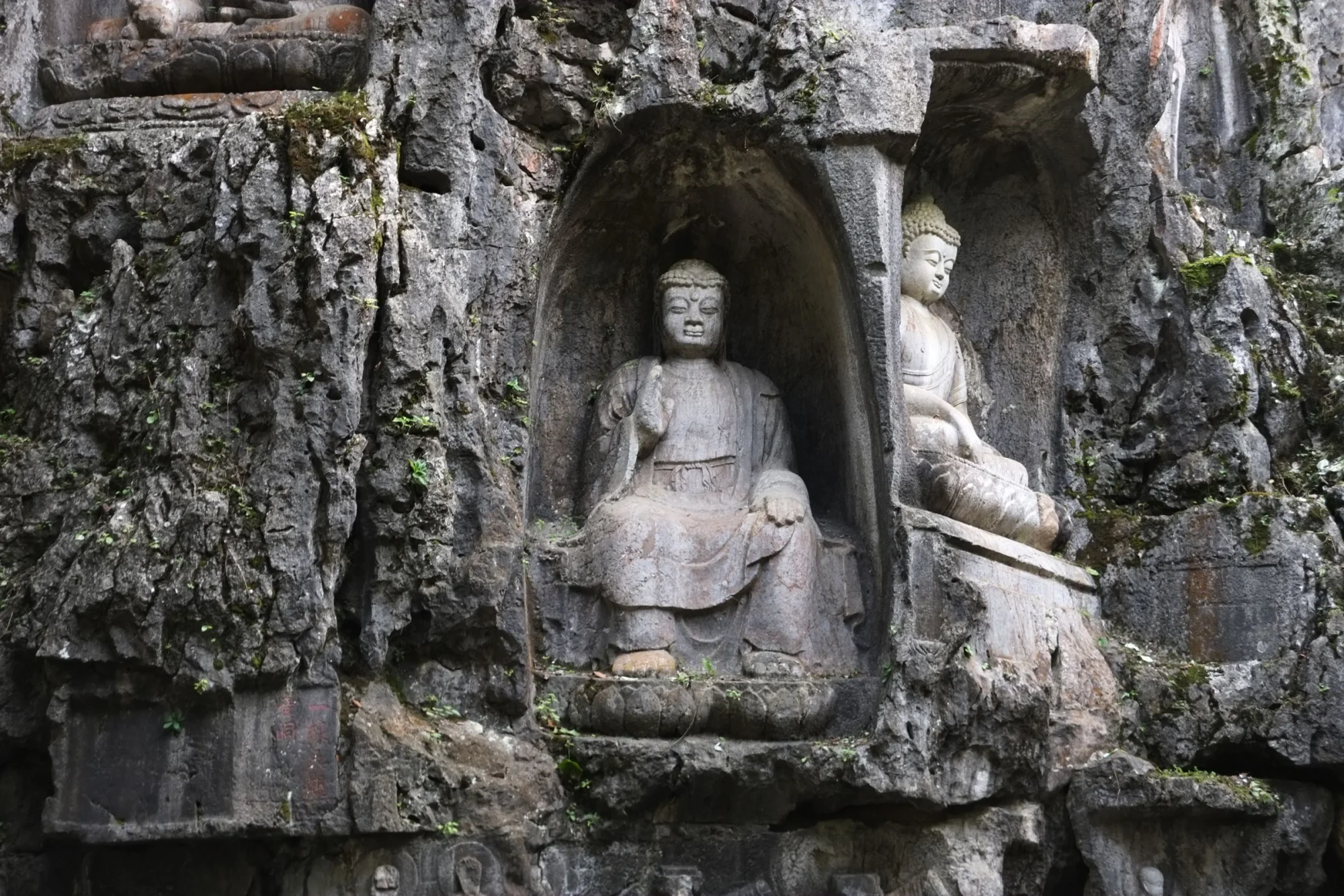 Eroded stone Buddha statues carved into a rock face at Lingyin Temple, Hangzhou.