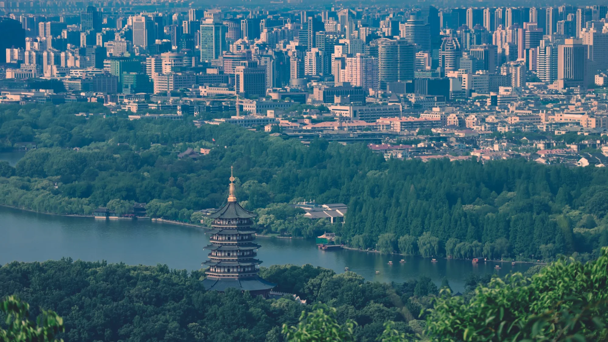 A breathtaking view of Leifeng Pagoda surrounded by lush greenery and urban skyline in Hangzhou, China.
