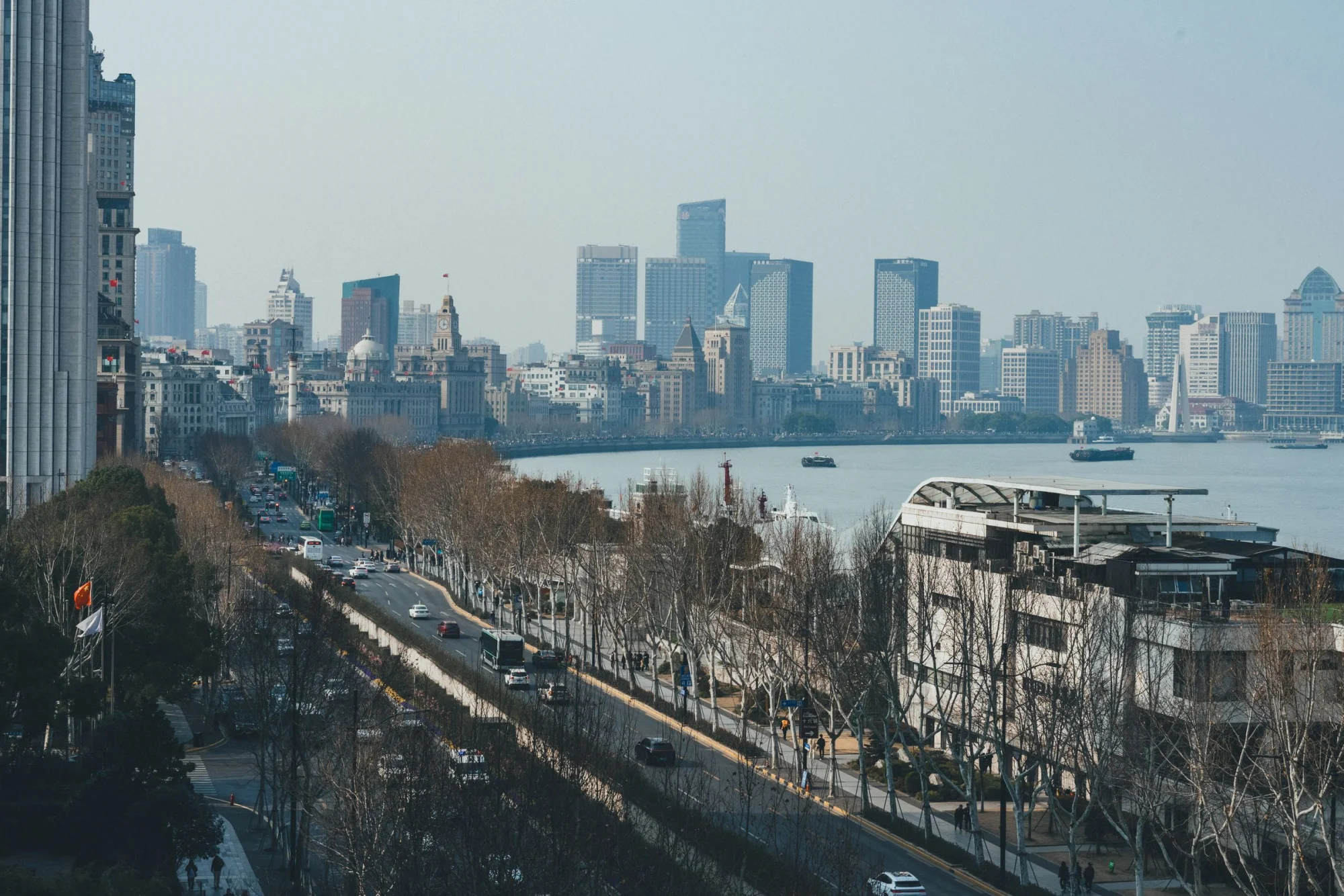 Aerial view of Shanghai's Pudong skyline across the Huangpu River from The Bund, capturing the modernity of the cityscape.