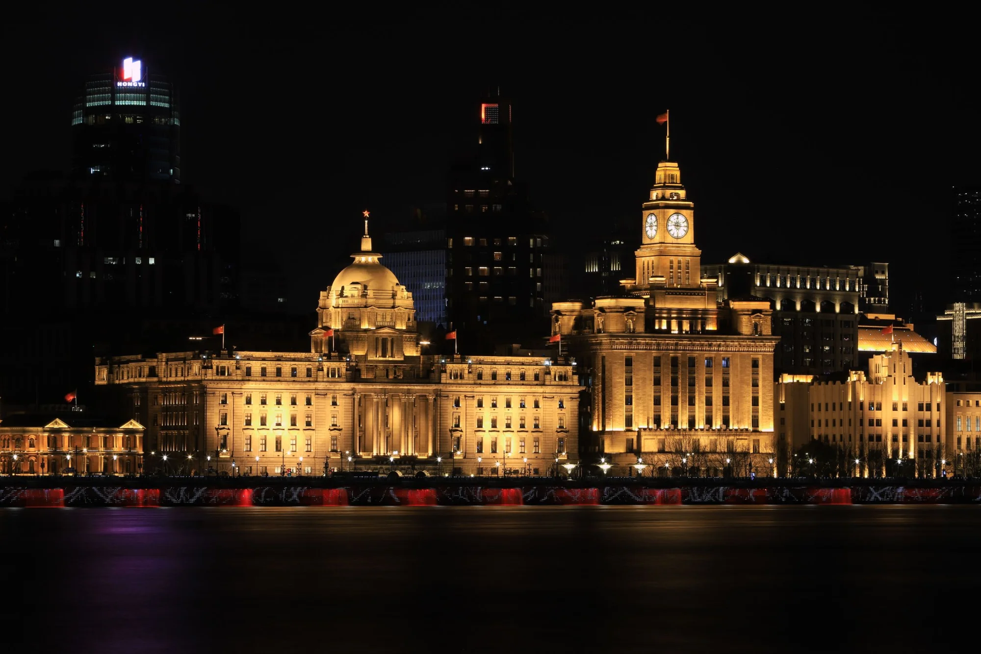 Night view of The Bund in Shanghai showcasing iconic historical buildings beautifully lit up.