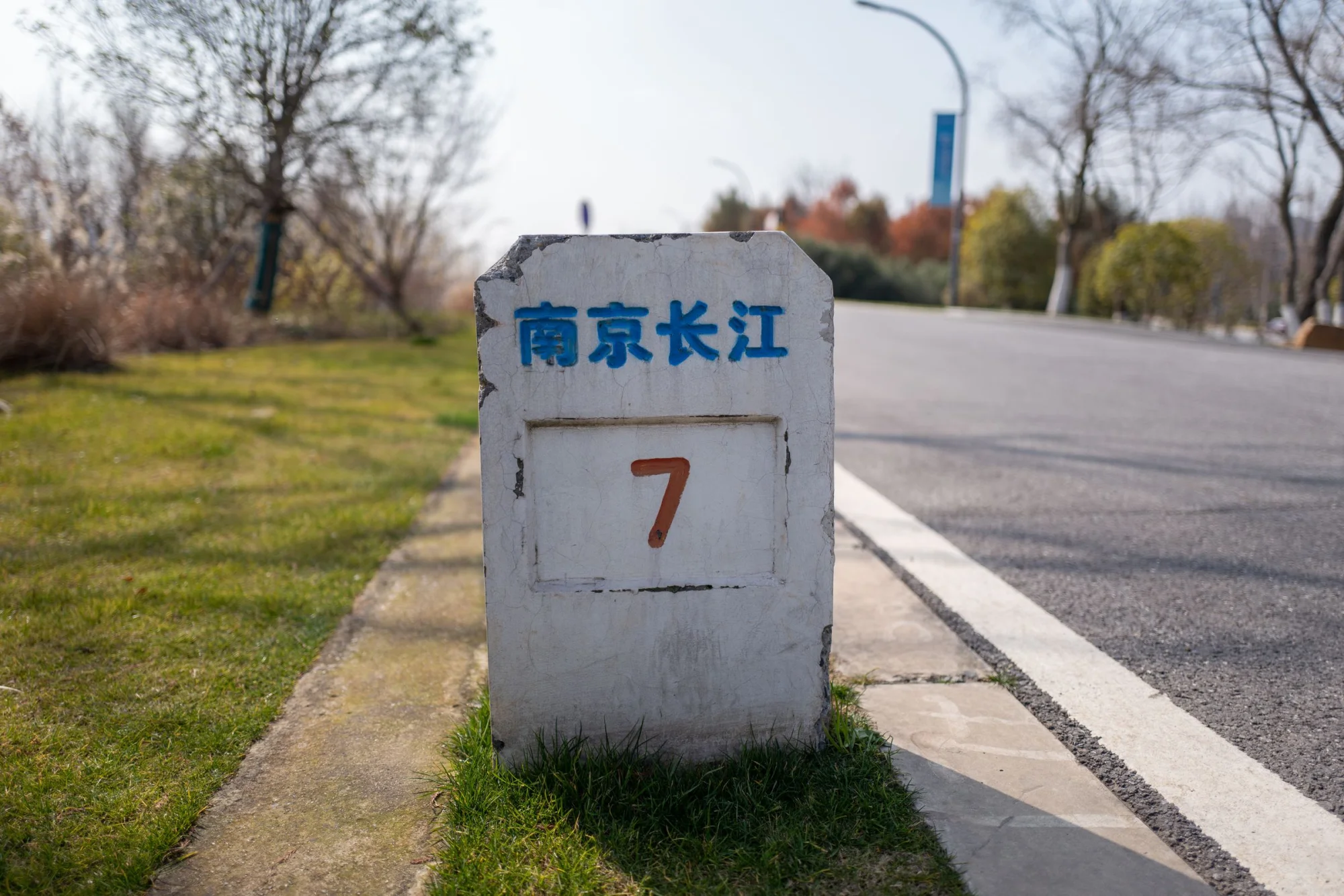 Concrete mile marker on a road in Nanjing, China, indicating distance with lush greenery around.