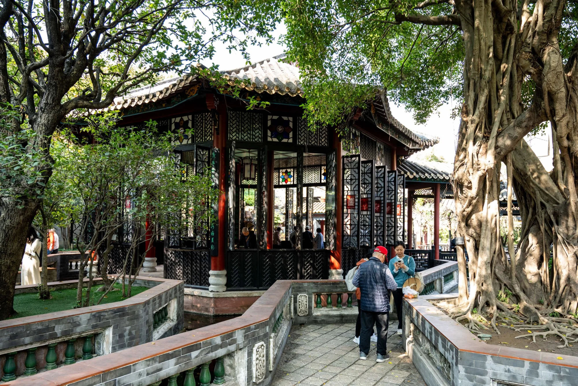 Scenic traditional Chinese pavilion in Zhongshan Park, Foshan, with people enjoying a sunny day outdoors.
