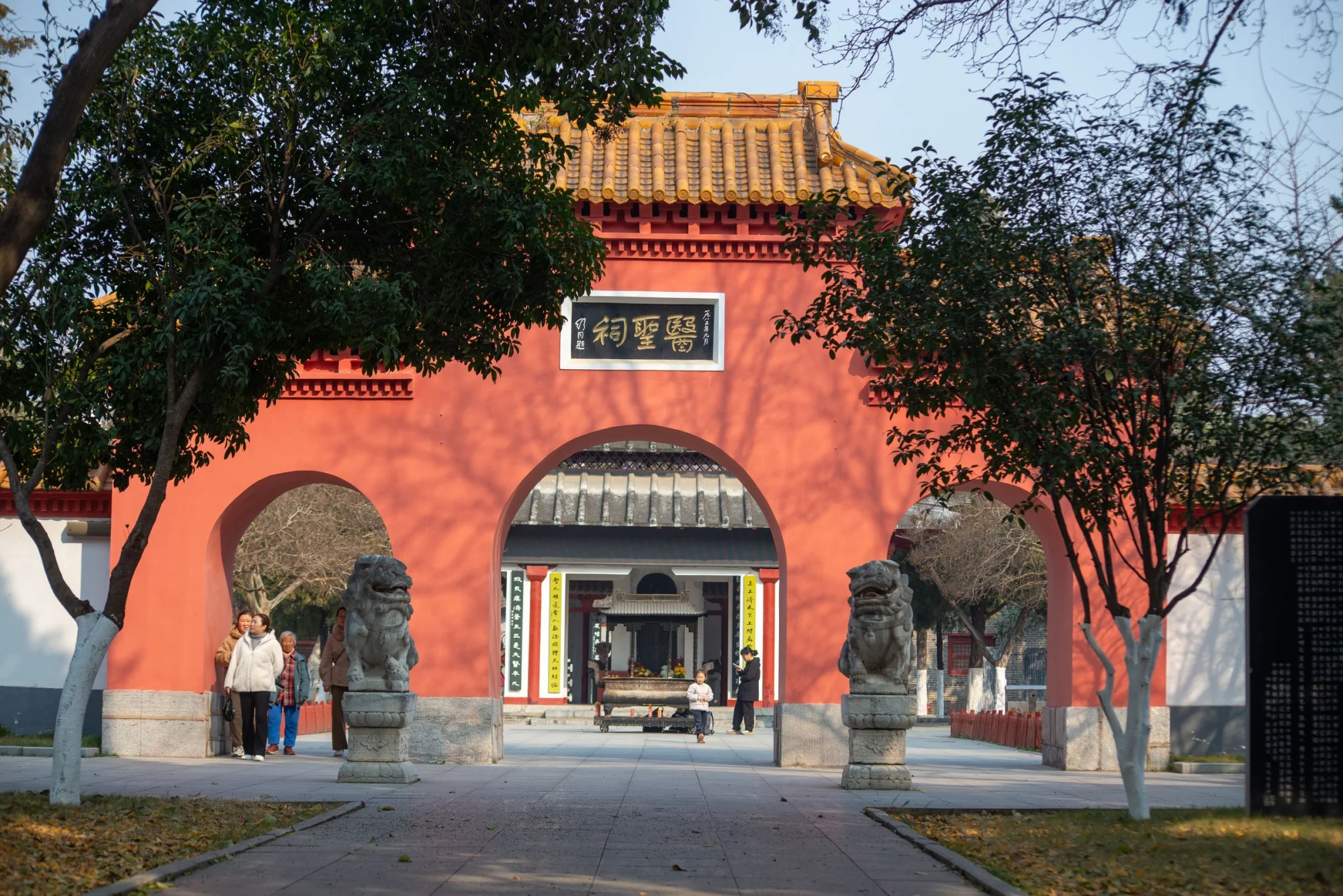 Beautiful traditional Chinese temple entrance with red walls and guardian lion statues, highlighting cultural architecture.