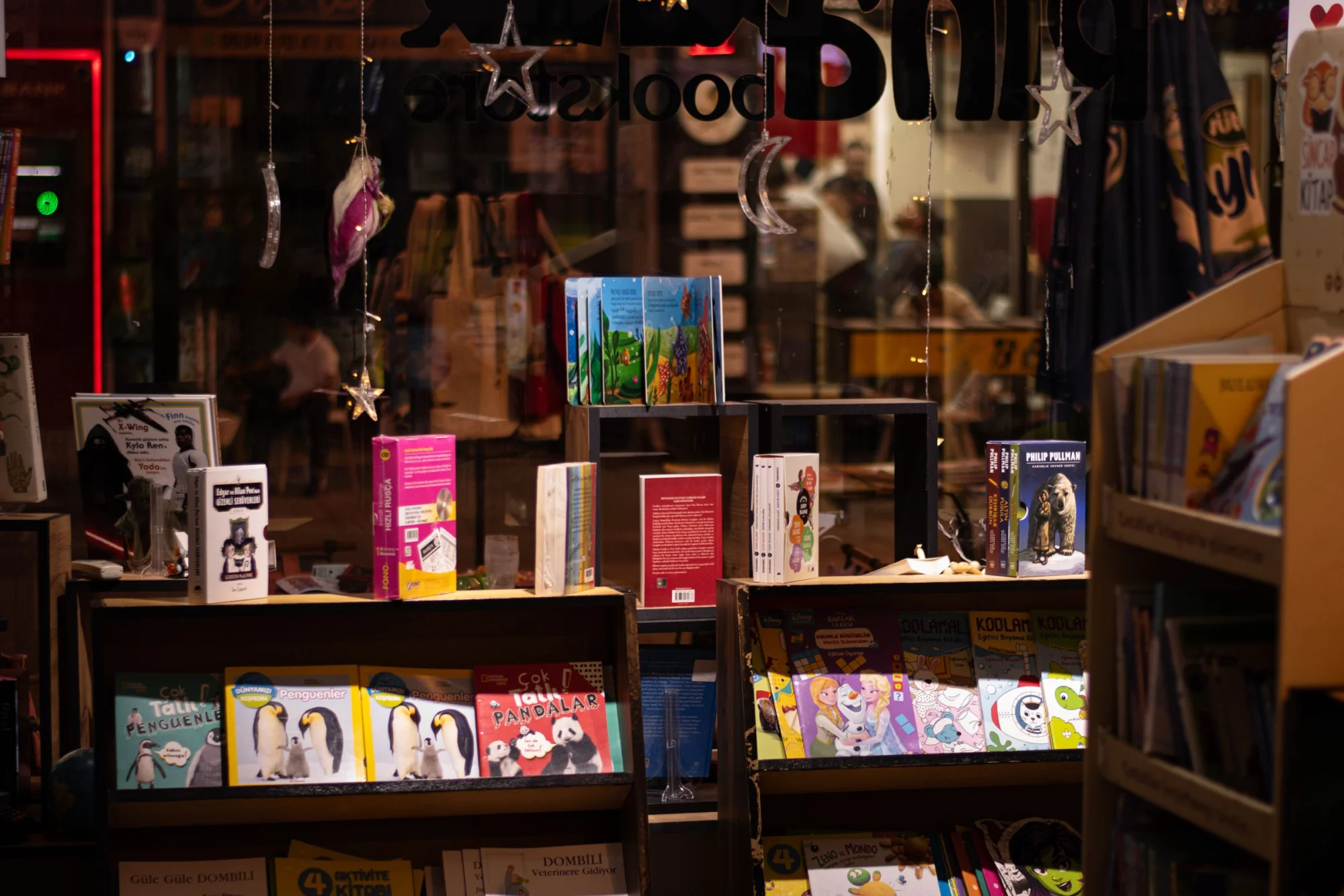 Warm and inviting bookstore window display showcasing colorful books at night.