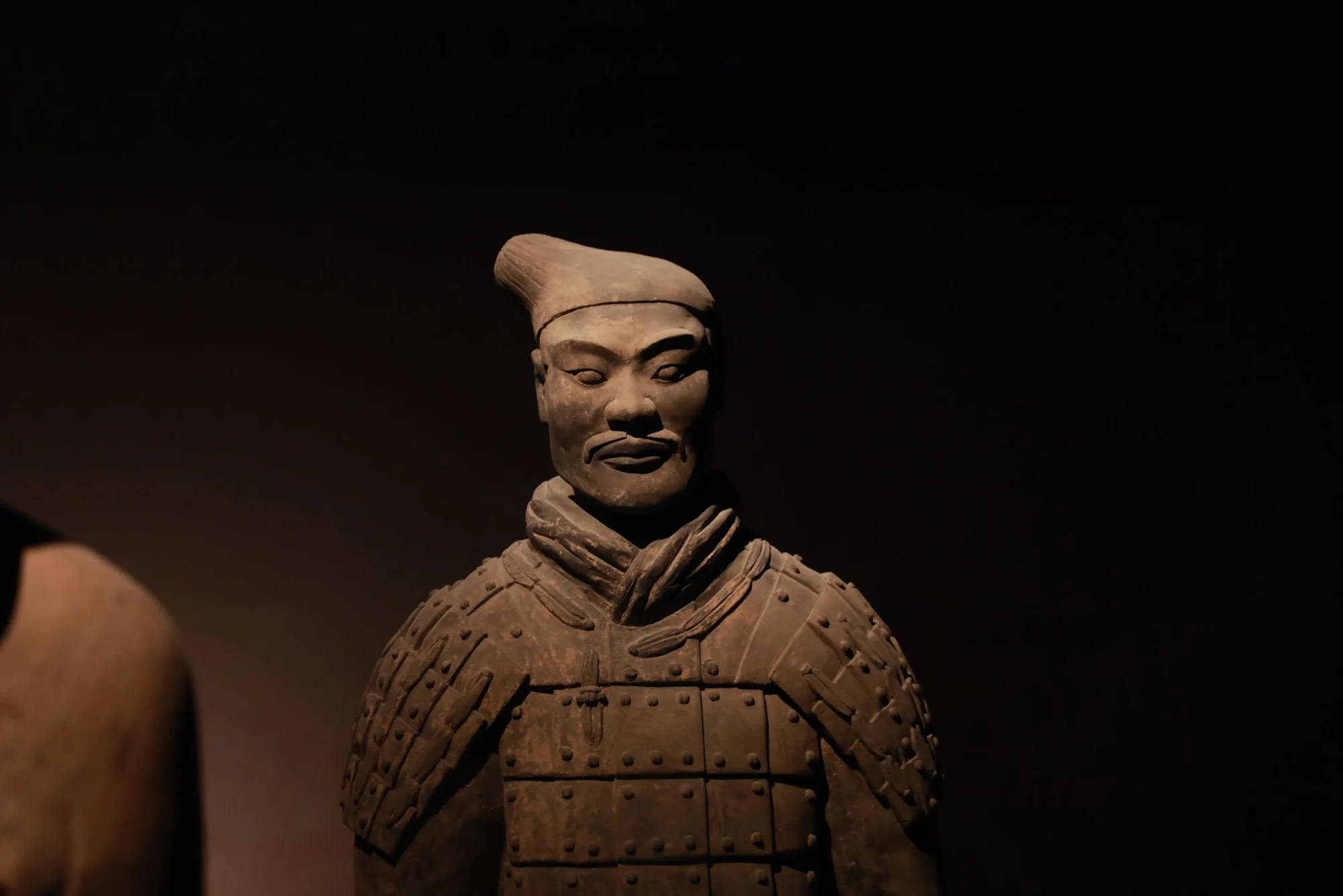 Close-up of a Terracotta Warrior statue with artistic lighting, capturing its detailed, historic features.